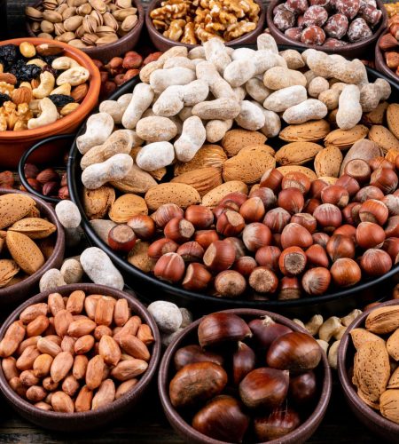 Set of pecan, pistachios, almond, peanut, cashew, pine nuts and assorted nuts and dried fruits in a different bowls . side view.